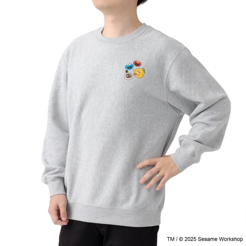 グレーのスウェットを着た男性。スウェットにはセサミストリートのキャラクターのイラストが描かれている。