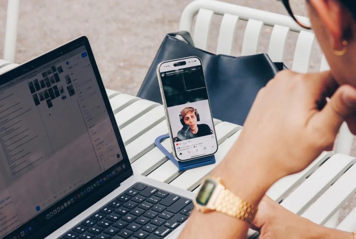 携帯電話でビデオ通話をしている人物のクローズアップ写真。電話は青い電話スタンドに置かれ、ビデオ通話の相手はヘッドフォンを着用している。