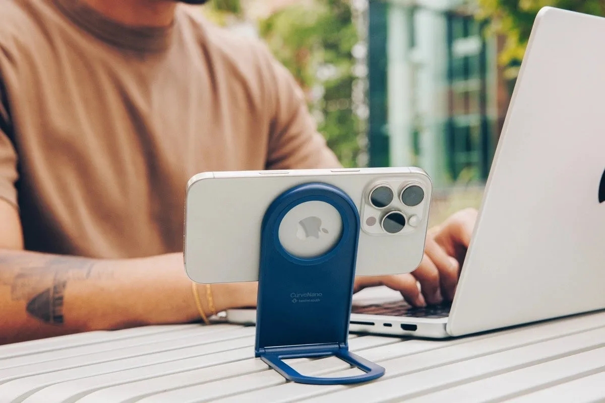 iPhoneがスタンドに立てかけられており、MacBook Proを使って作業している様子