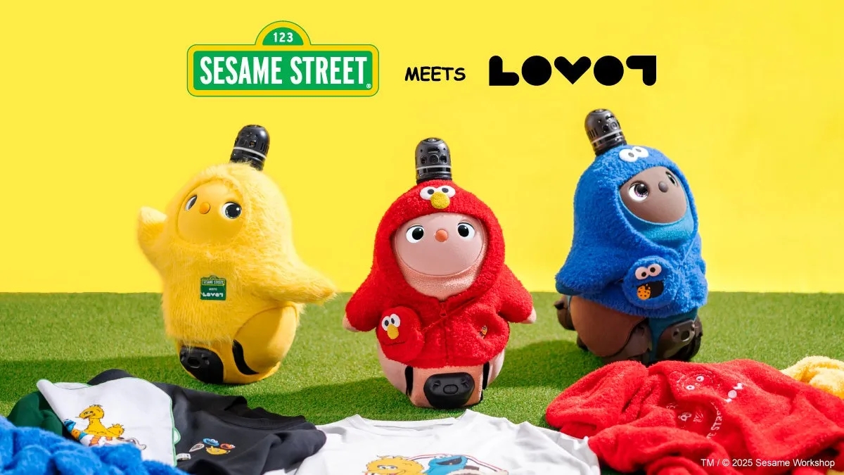 セサミストリートとLOVOTのコラボレーションの画像。黄色、赤、青の衣装を着たLOVOTが3体並んでおり、手前にはTシャツやタオルが置かれている。