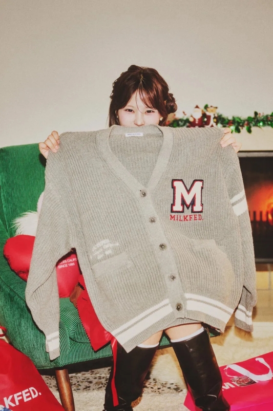 女性が「MILKFED」ロゴのグレーのカーディガンを持ち、顔を隠すようにしている画像