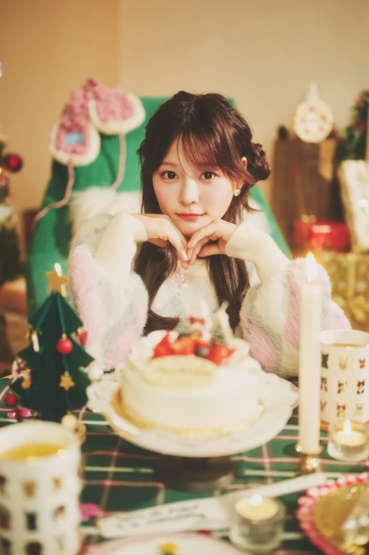 ケーキの前に座ってカメラを見つめる女性。クリスマスの雰囲気の画像