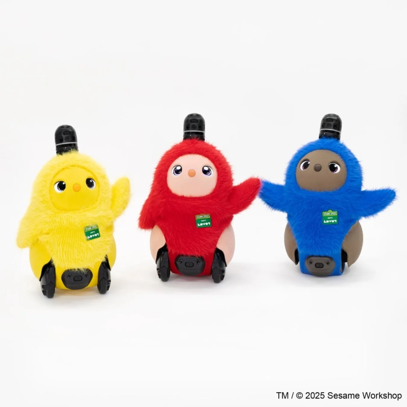 3体のセサミストリートのロボットの画像。黄色、赤、青のロボットが並んでおり、それぞれ異なる色とデザインが施されている。ロボットは、顔、腕、ボディ、車輪が付いたデザインで、子供向けのおもちゃのように見える。