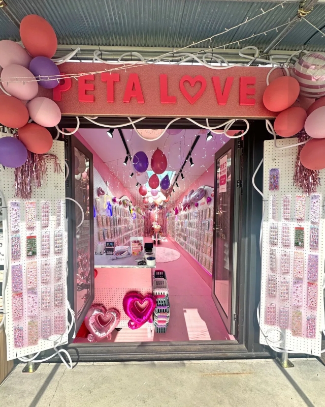 ピンク色の内装で、風船やアクセサリーが飾られたお店の入り口の写真です。「PETA LOVE」の文字が看板にあり、ハートの風船が飾られています。
