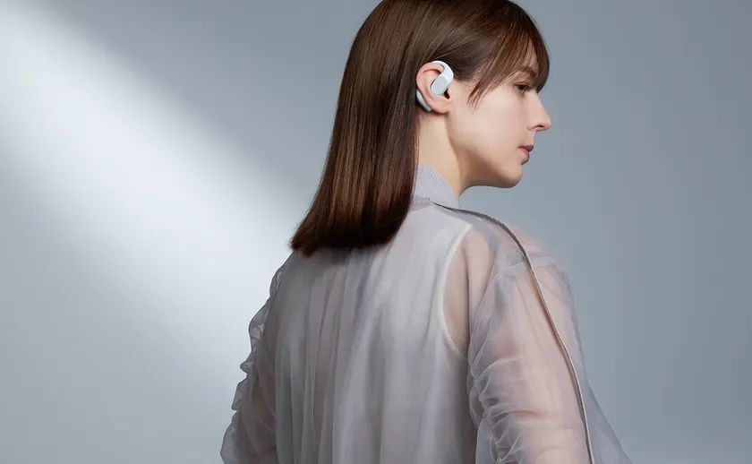 白いワイヤレスイヤホンを装着した女性の横顔のポートレート。