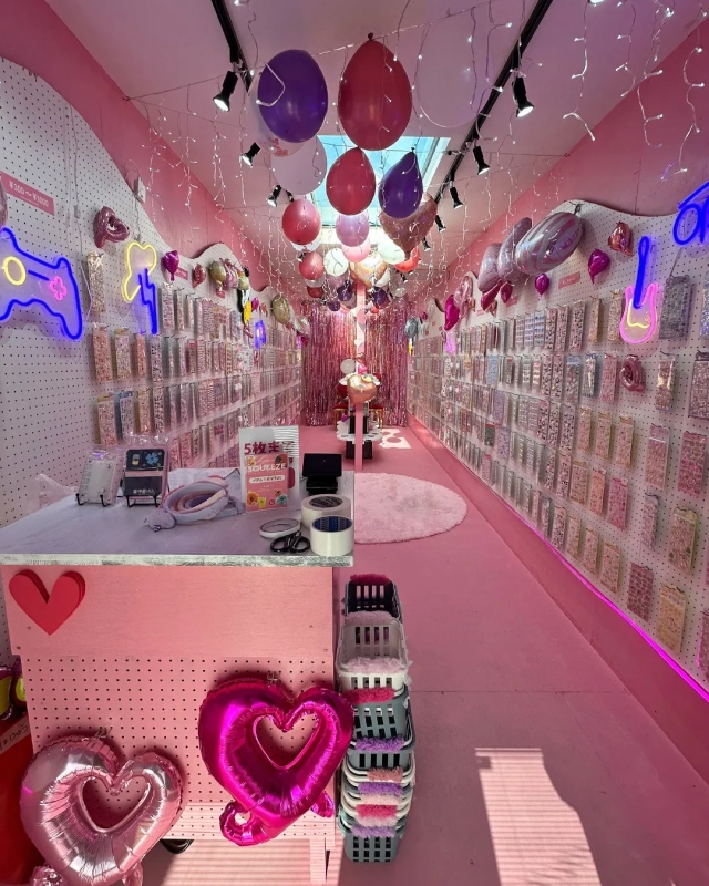 ピンクを基調とした内装の店内で、風船や商品が陳列されている様子を捉えた写真です。