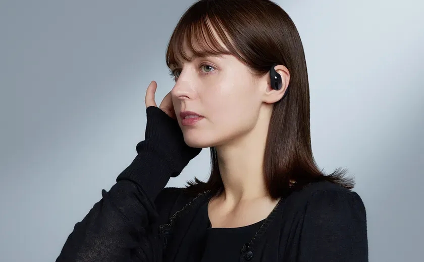 黒いイヤホンを右耳に装着した女性のクローズアップポートレートです。