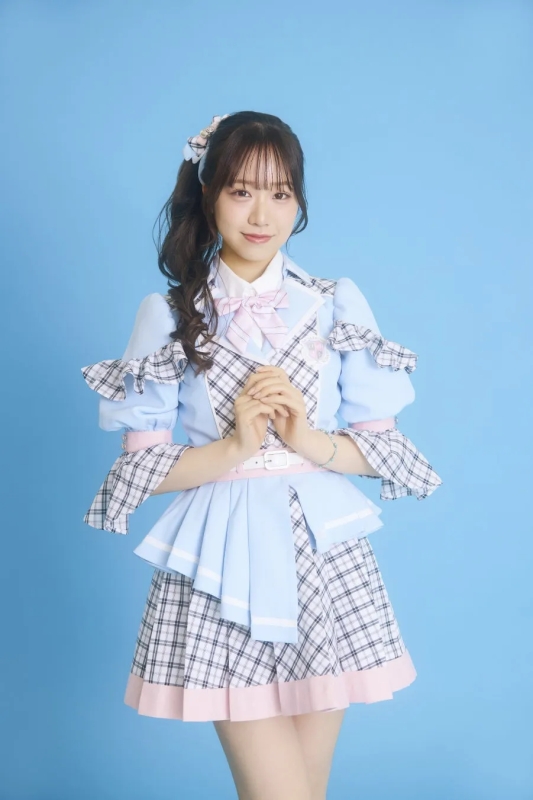 水色の衣装を着た女性のポートレート。彼女は髪をポニーテールにし、ピンクのリボンで飾っています。背景は水色です。