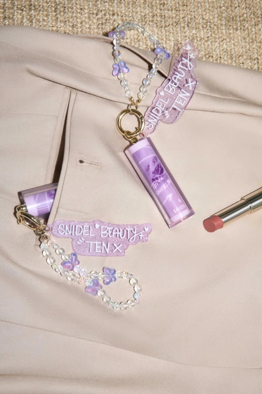 ベージュのジャケットの上に置かれたリップスティックとアクセサリー