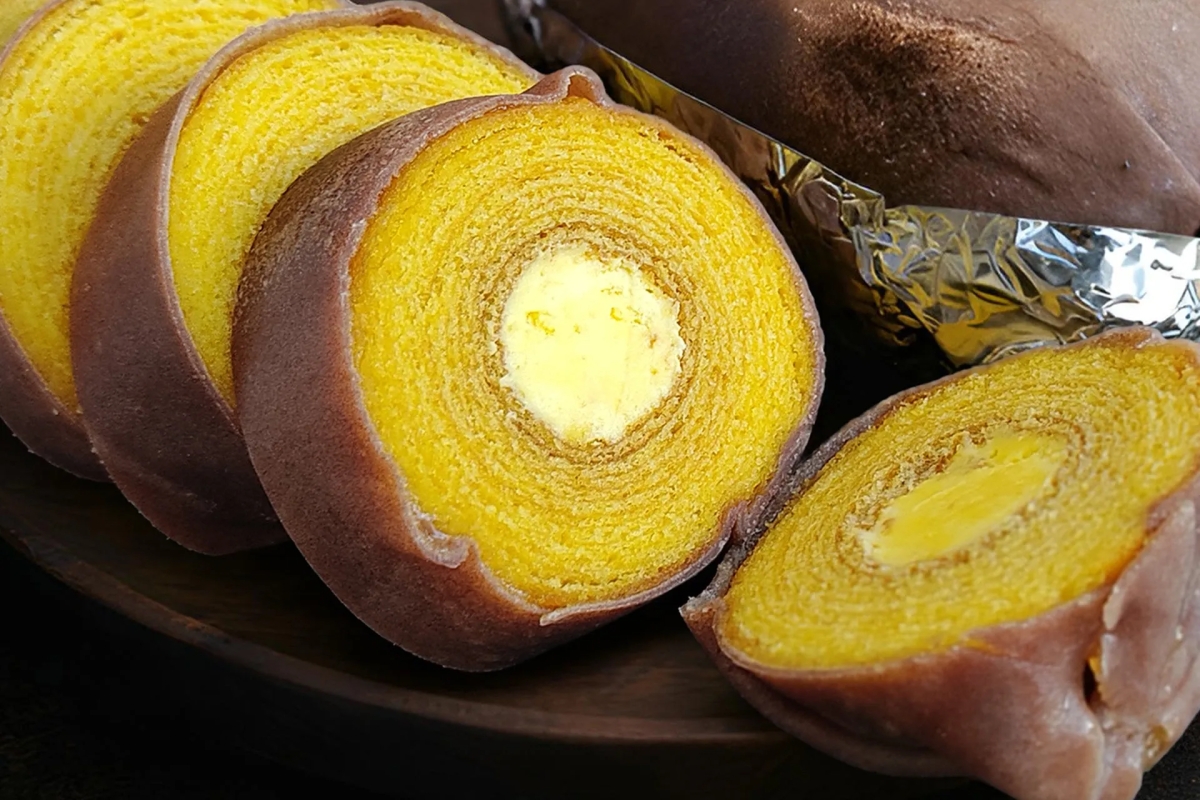 バウムクーヘンがカットされた写真です。バウムクーヘンは黄色く、中心にクリームが入っています。茶色の容器に置かれています。