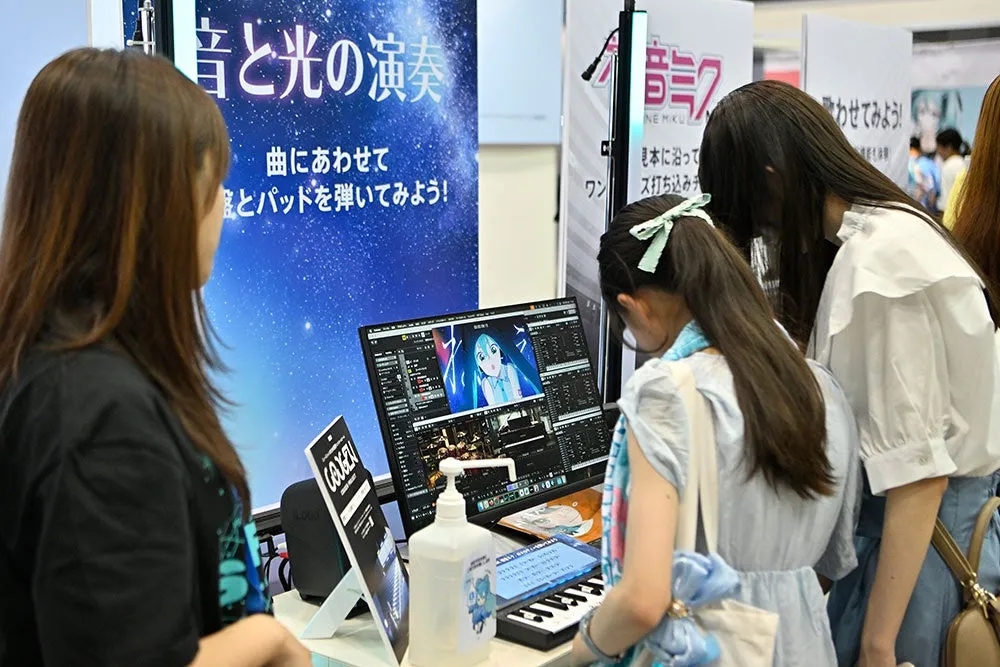 展示会で、モニターを見ながらキーボードを演奏している女性たち。