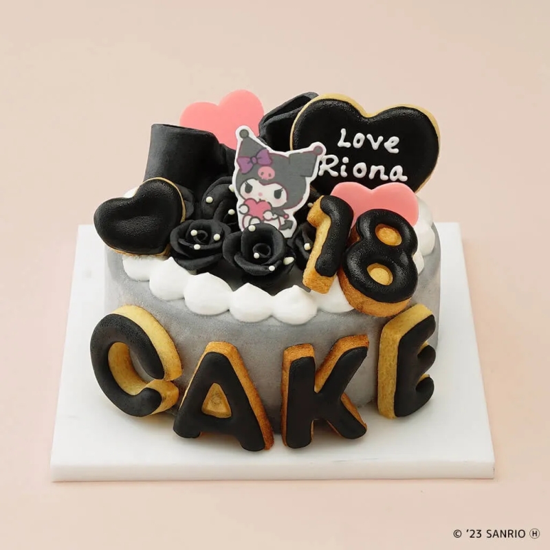 クロミのキャラクターケーキ。黒とピンクを基調としたデザインで、クッキーでできた「CAKE」の文字と18の数字が目を引く
