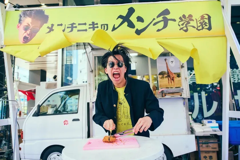 屋台でメンチカツを切る男性