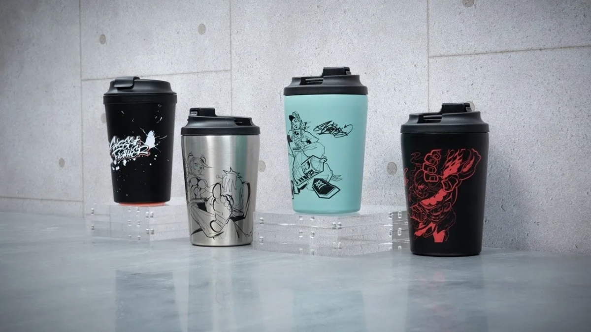 4つのタンブラーが並んでいる画像。タンブラーにはそれぞれ異なるイラストが描かれており、黒、シルバー、水色、黒の4色で、すべて黒い蓋が付いている。タンブラーは透明な台の上に置かれ、背景はコンクリートのような質感の壁。