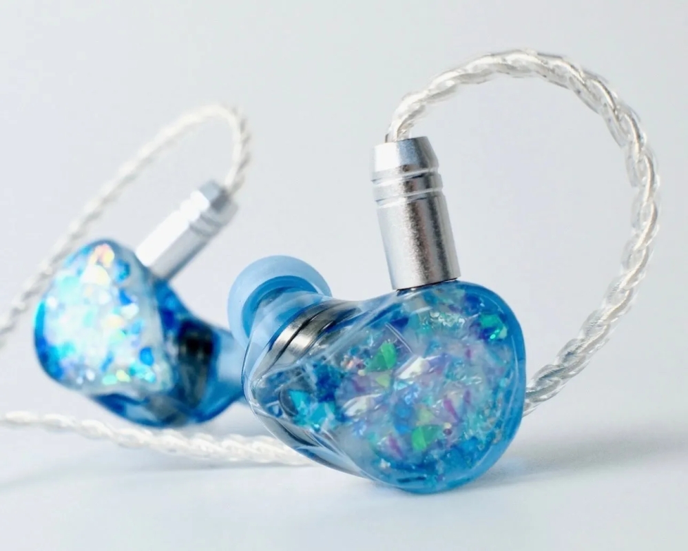 青色のイヤホンが2つ並んだ写真。イヤホンはキラキラしたデザインで、ケーブルは白っぽい色をしている。
