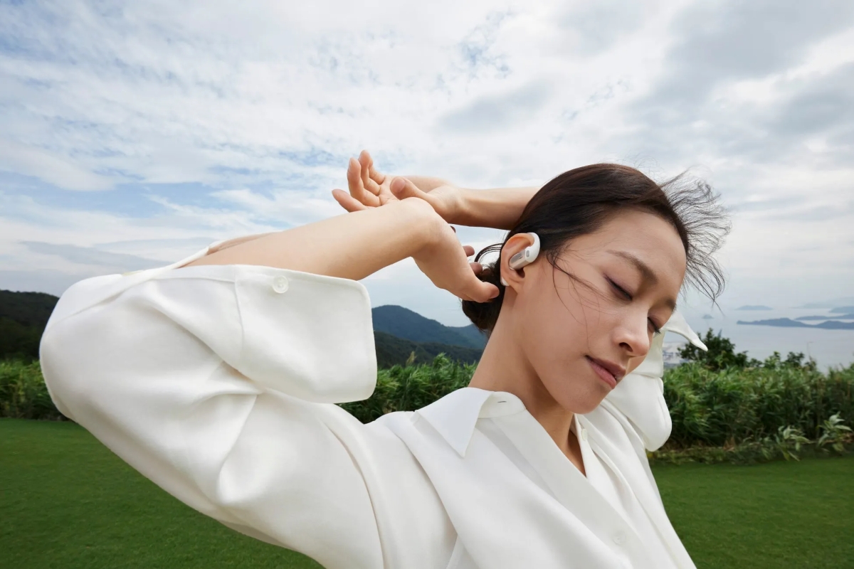 女性がイヤホンを付けて屋外でリラックスしている様子。