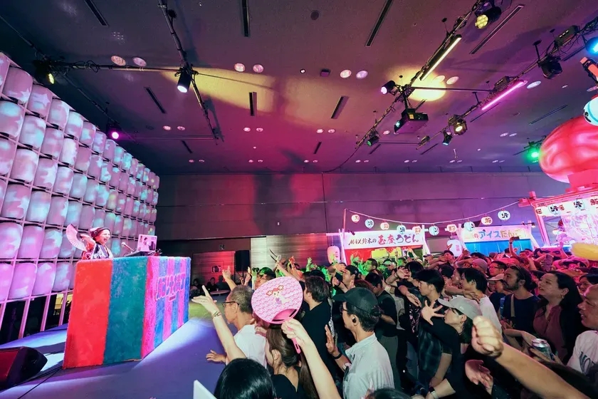 観客を前にパフォーマンスをする女性と、それを見守る観客の様子