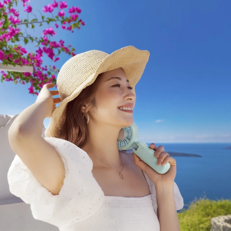 女性が扇風機を持ち微笑んでいる