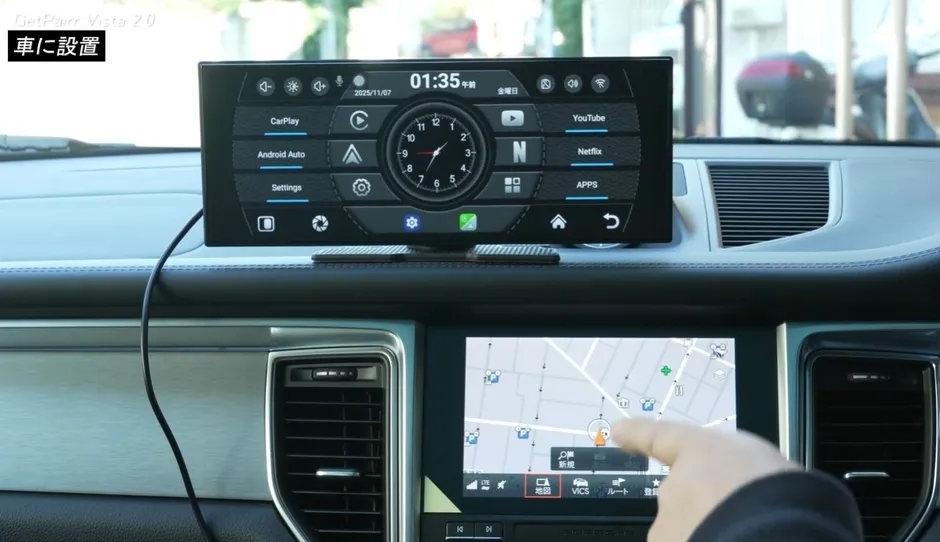 車のダッシュボードに設置されたカーナビゲーションシステム。上部には時刻やアプリへのショートカットが表示され、下部には地図が表示されている。