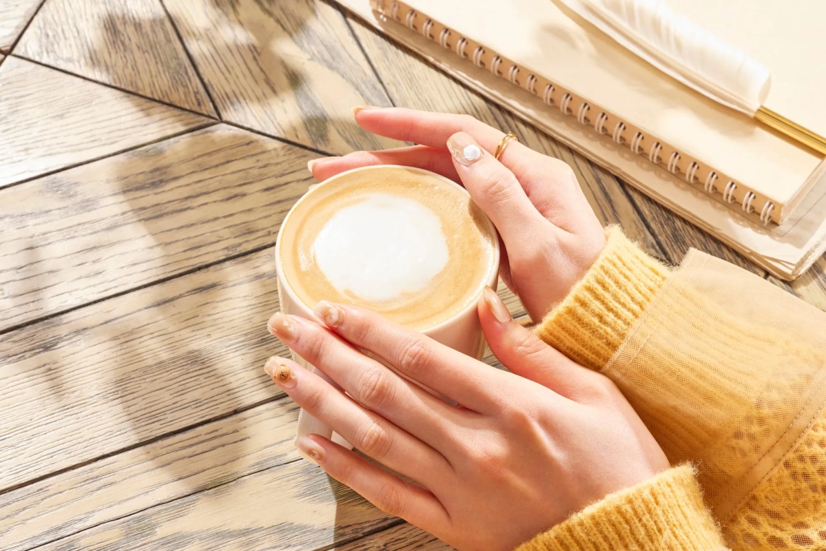 カフェラテを手で持っている様子が写っています