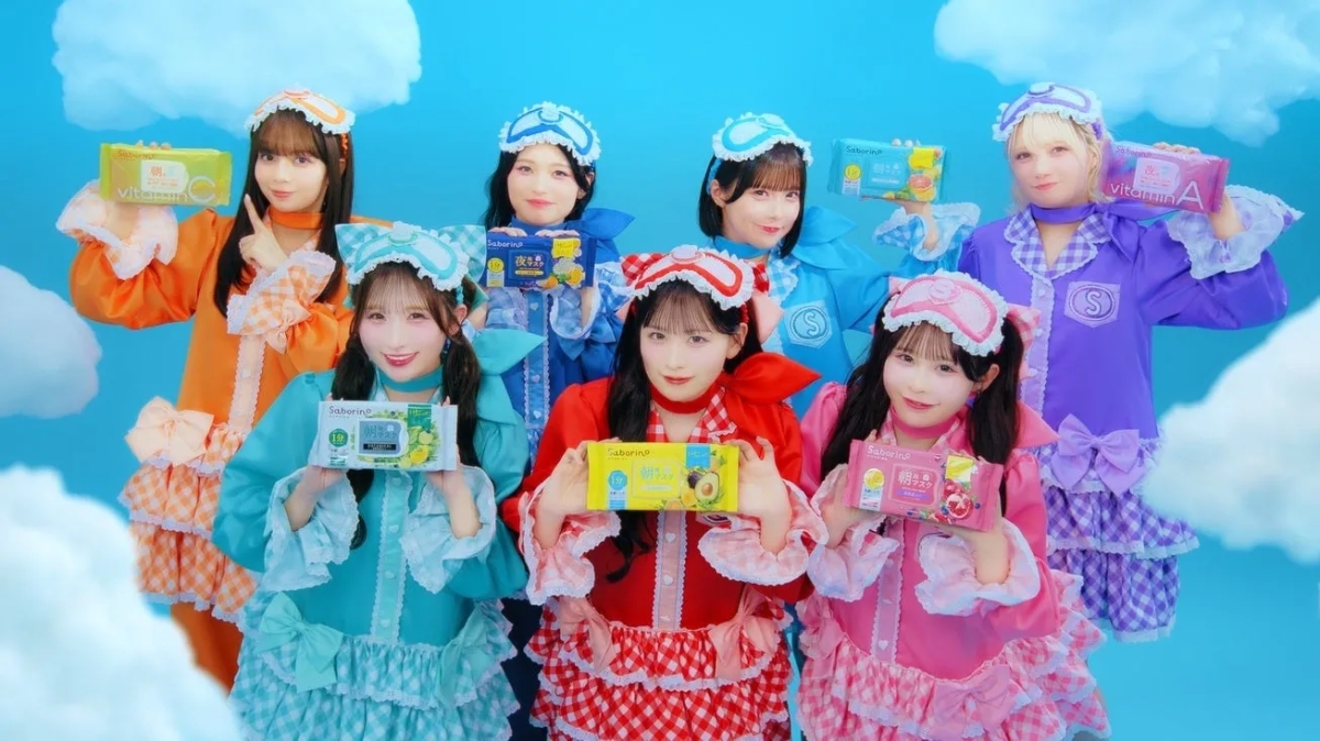 青空と雲を背景に、カラフルなパジャマ風衣装の7人の女性が笑顔でSaborinoフェイスマスク製品を紹介しています。朝用、夜用、ビタミン配合など様々な種類が見られ、明るくポップな美容商品のプロモーション画像です。